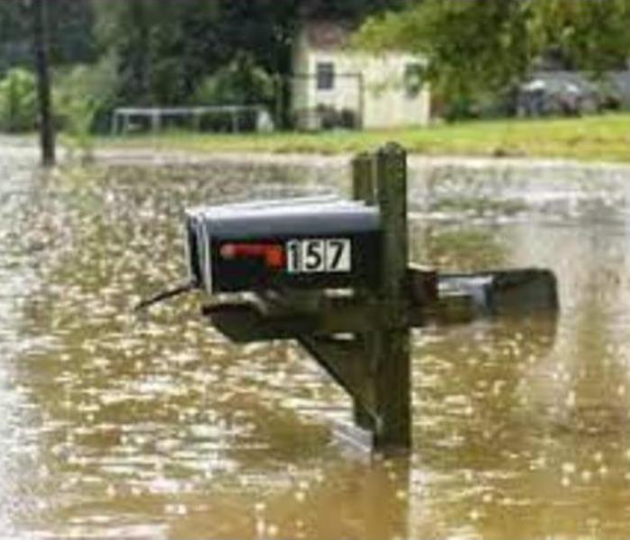 Flooded street with a water halfway up a mailbox post